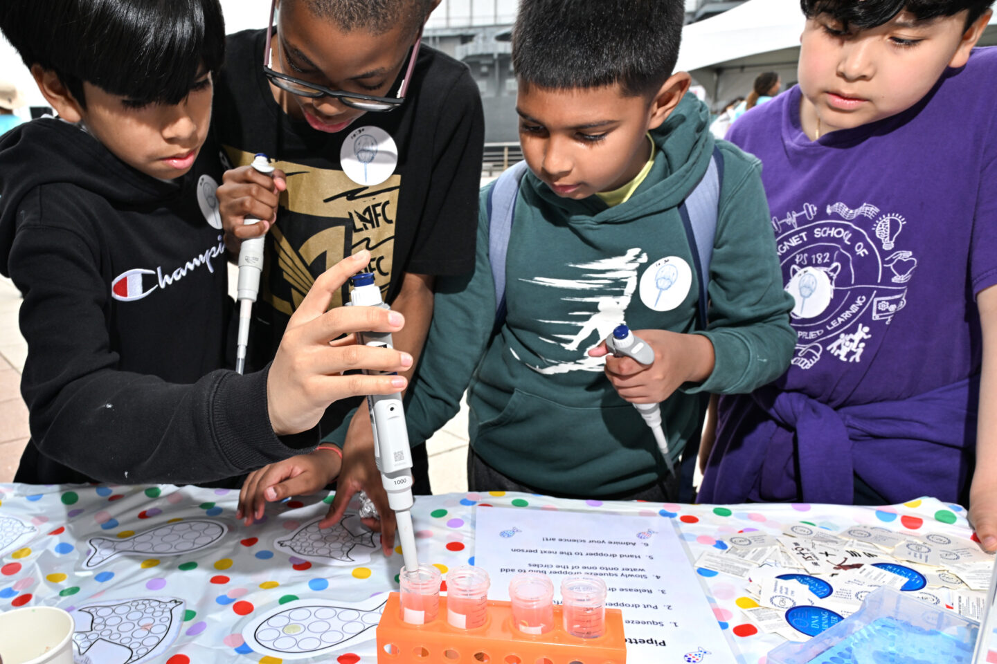 Four students use pipettes during an activity at a SUBMERGE Marine Science Festival booth