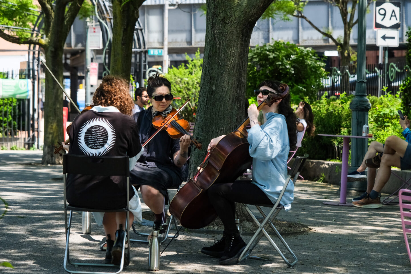 Aliya Ultan, Marija Kovačević and Rachel Feldhaus play string instruments at 14th Street Park as part of a Matinee Music concert