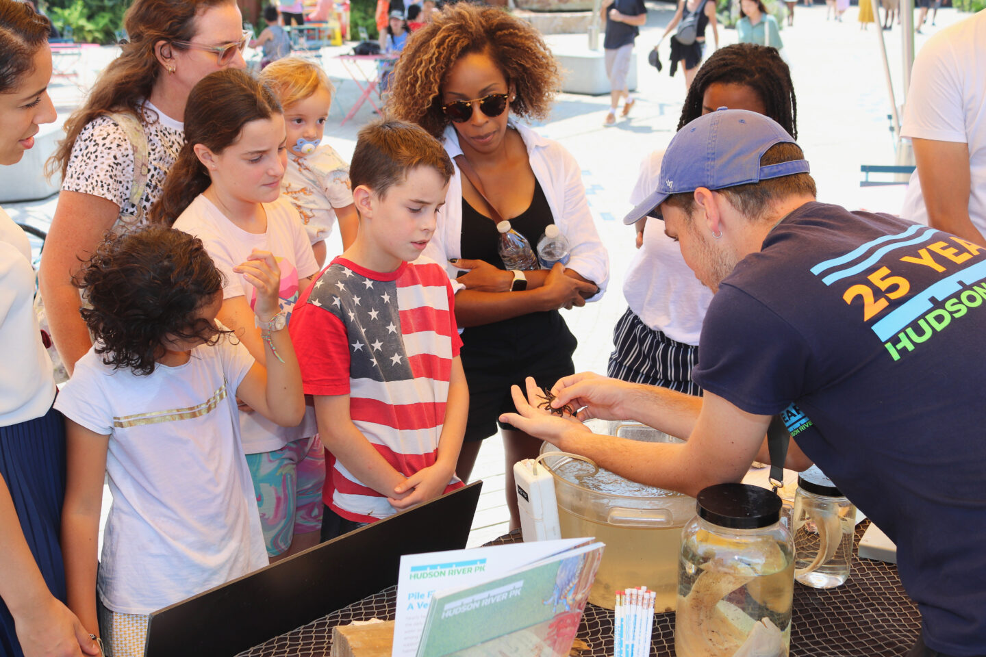 An HRPK River Project staffer shows kids and adults a small crab that lives in the Hudson River