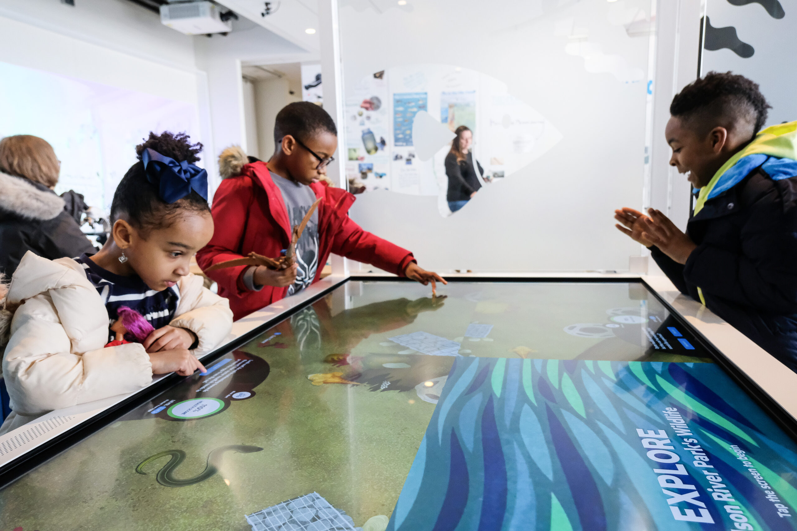 Students interact with a tabletop touchscreen display at the Pier 57 Discovery Tank