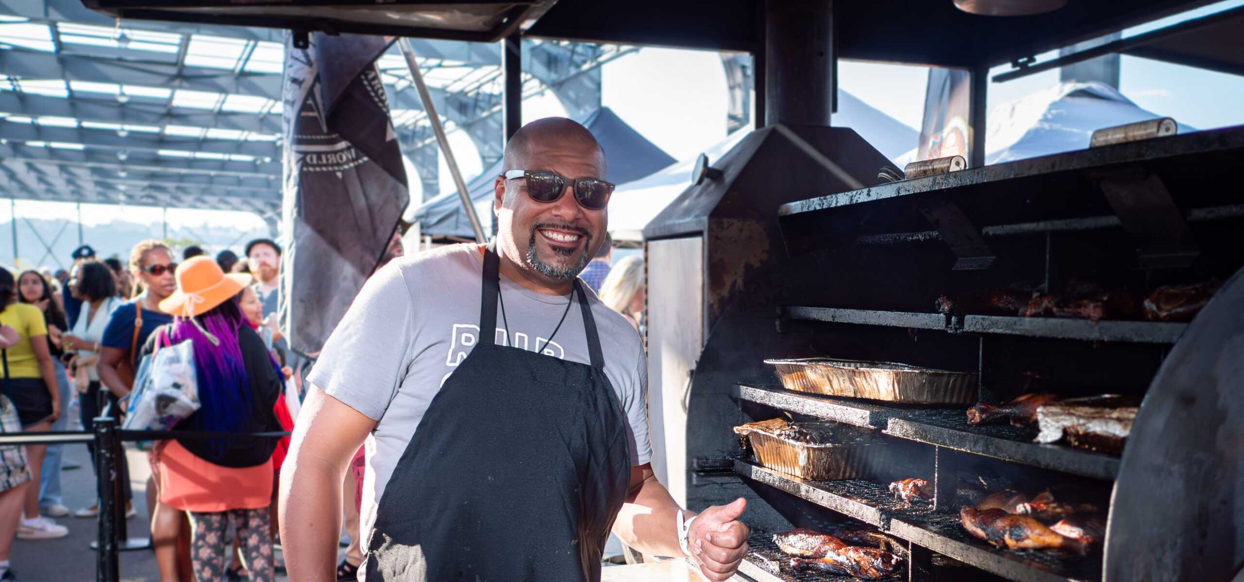 A cook smiling and posing next to a grill at the Blues BBQ Festival