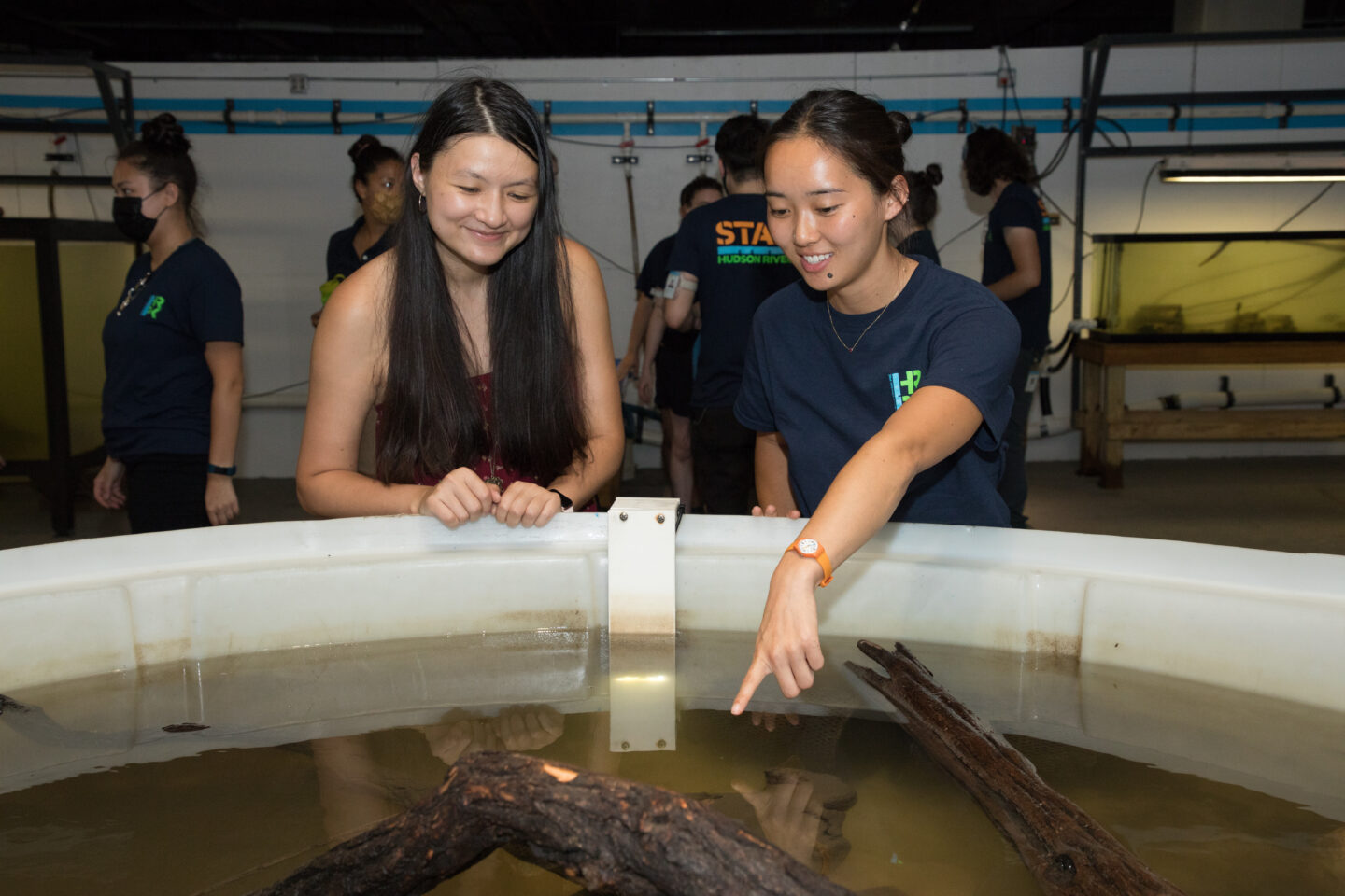 A Hudson River Park River Project staffer teaches a Pier 40 Wetlab visitor about wildlife near an aquarium pool