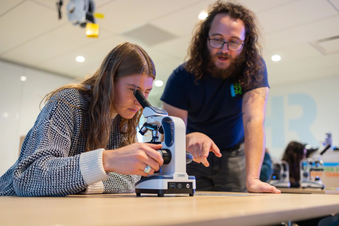 A person looks into a microscope while a Hudson River Park River Project staffer explains what they're seeing under the microscope