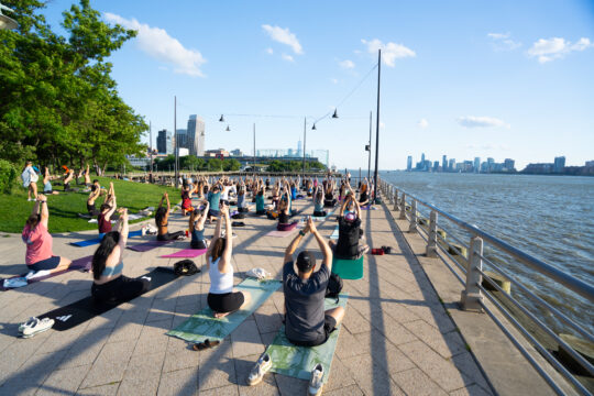 Healthy on the Hudson Yoga class participants stretch on Pier 64