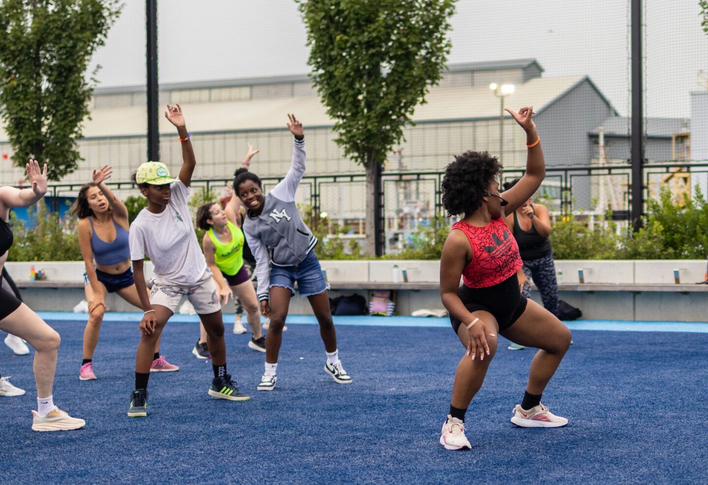A group fitness instructor leads a class of Healthy on the Hudson participants in a stretch on the Pier 97 Athletic Field