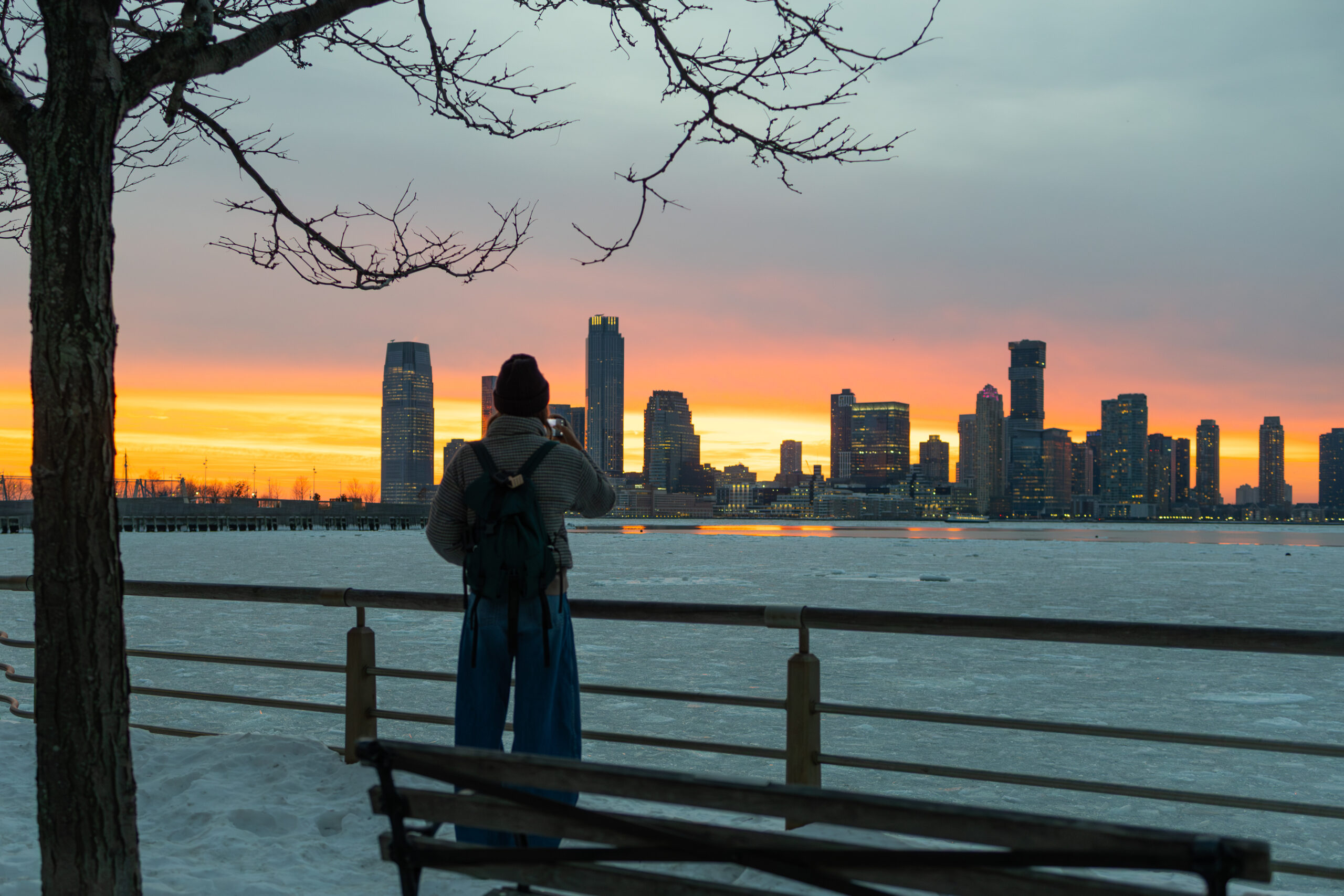 sunset over snowy waterfront, person taking photo, in Tribeca in Hudson River Park