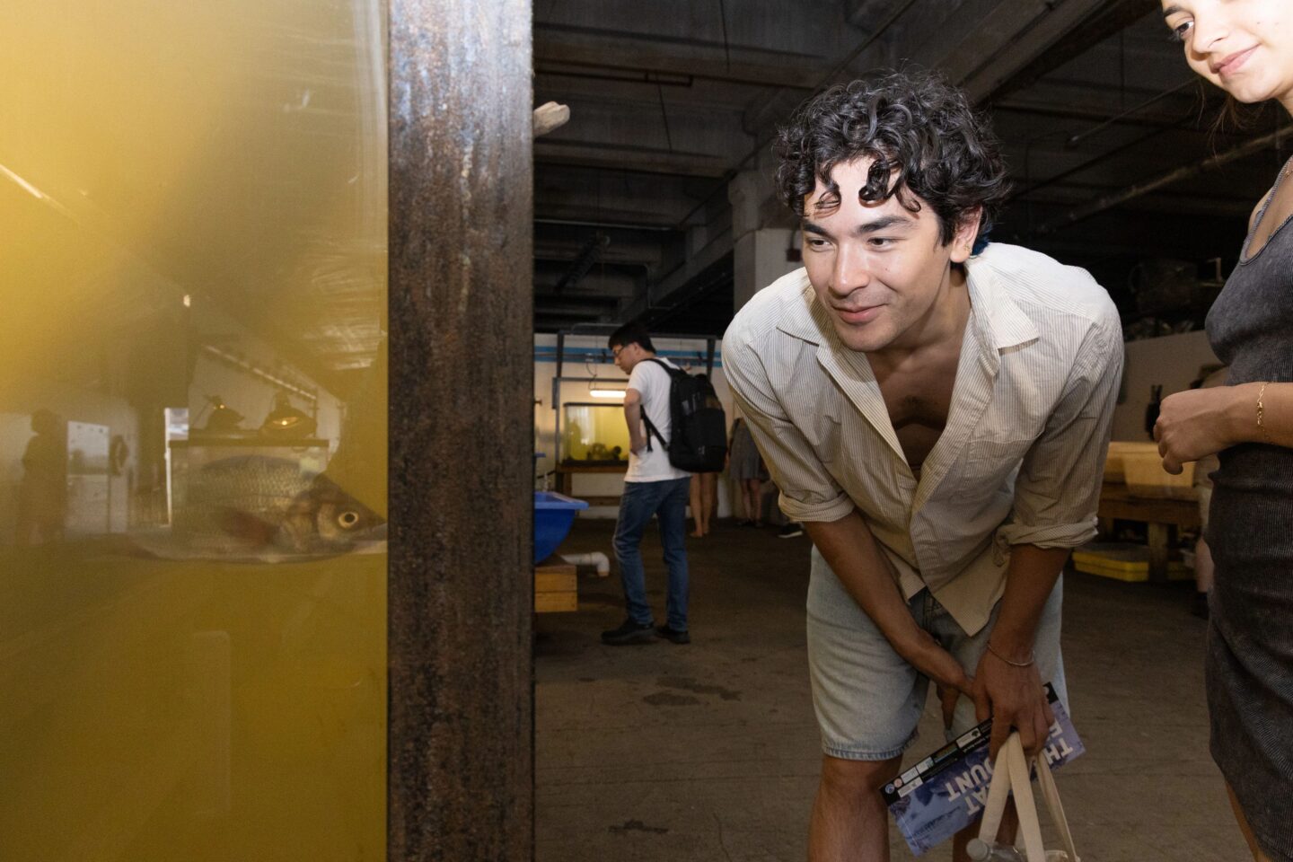 A person looks into an aquarium tank with fish inside at the Pier 40 Wetlab