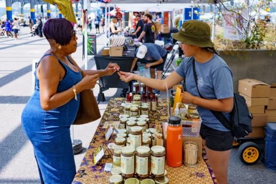 A hot sauce vendor offers a sample to a Blues BBQ Festival attendee