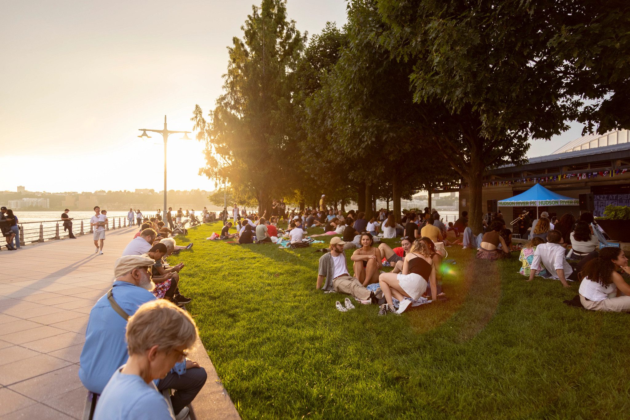 People sitting on the lawn and on benches during a Jazz at Pier 84 concert