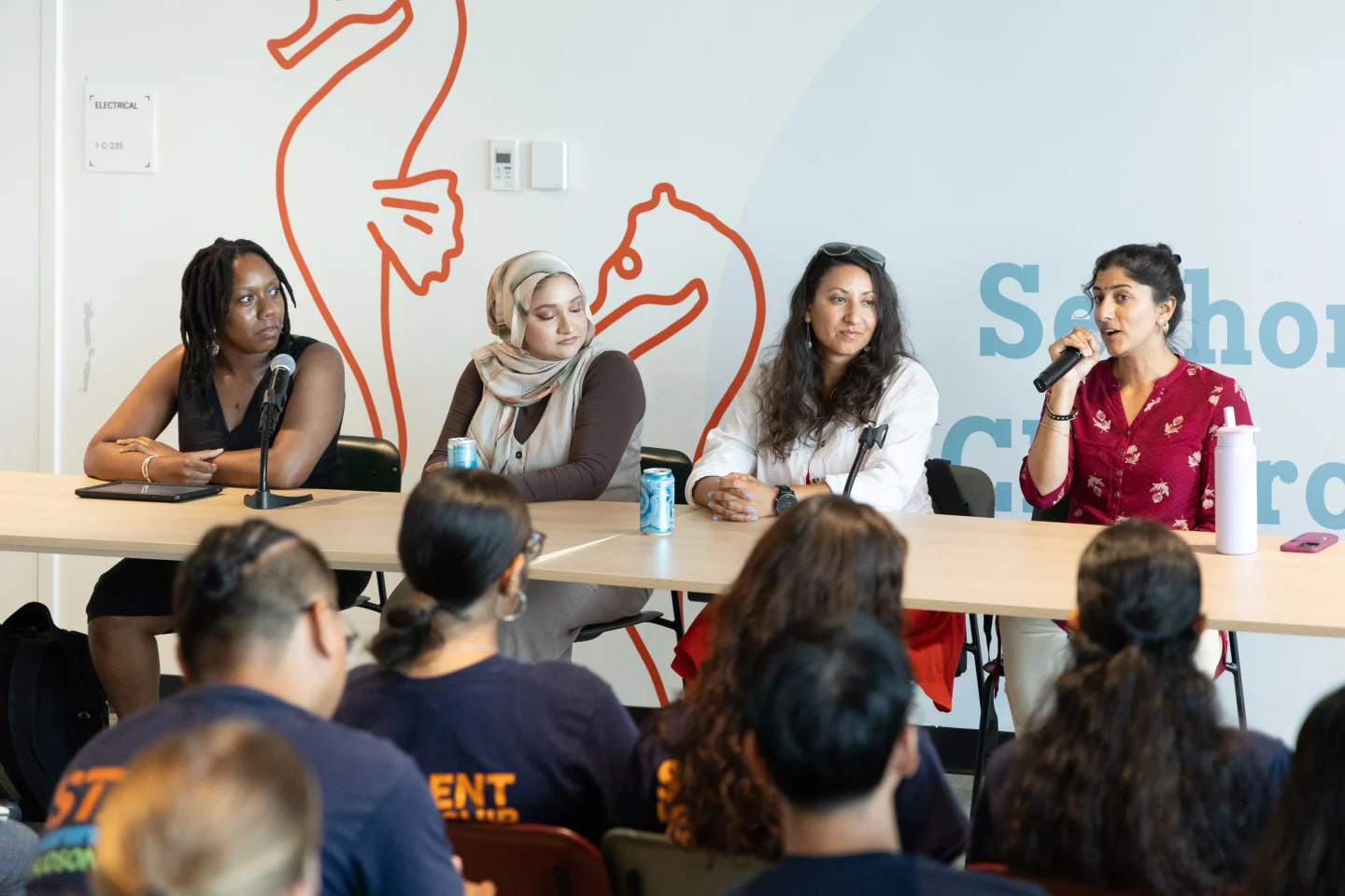 Four presenters seated at a table speaking to an audience at the Pier 57 Discovery Tank Classroom