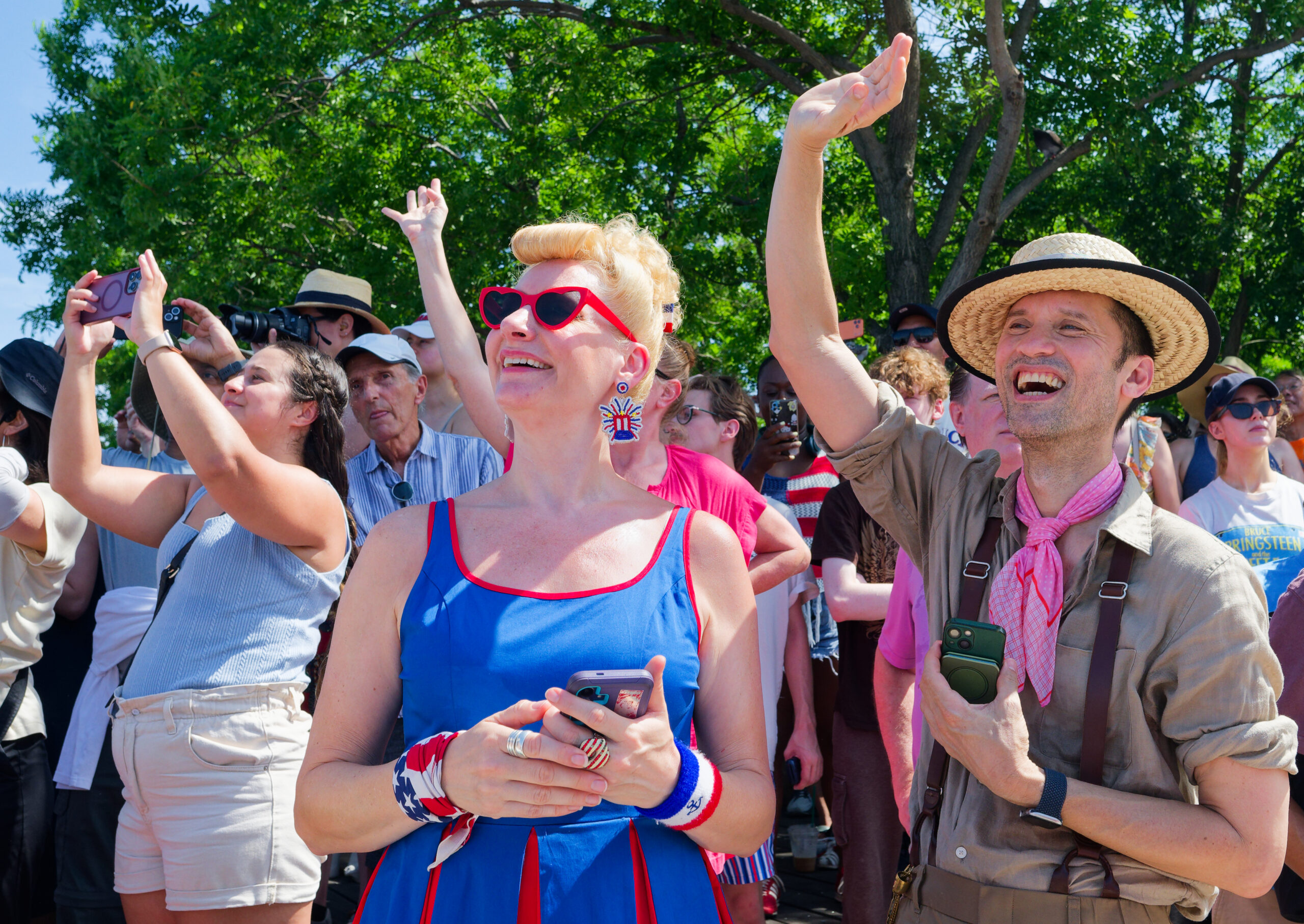 Crowd of people waving in front of trees