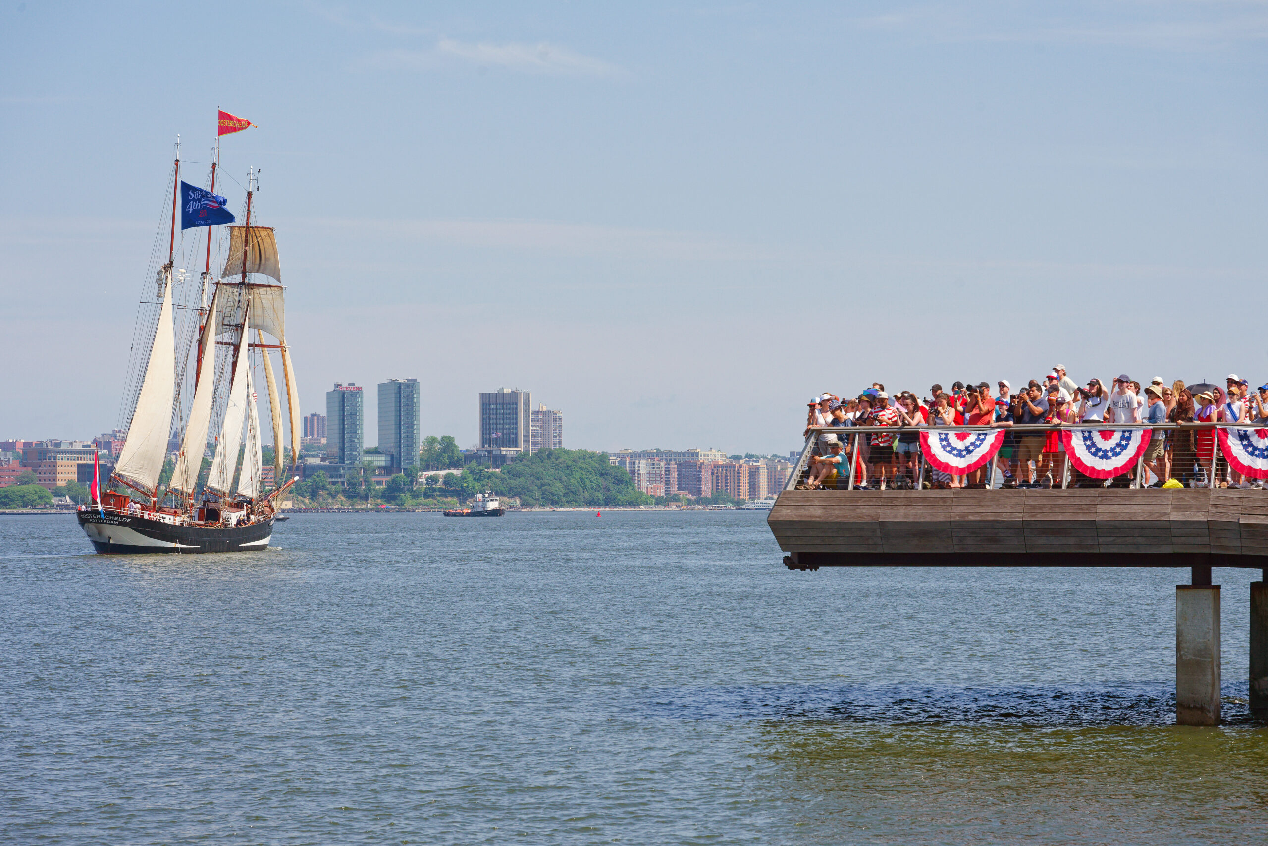Crowds gathered at edge of Pier 26 with tall ship sailing by on Hudson River