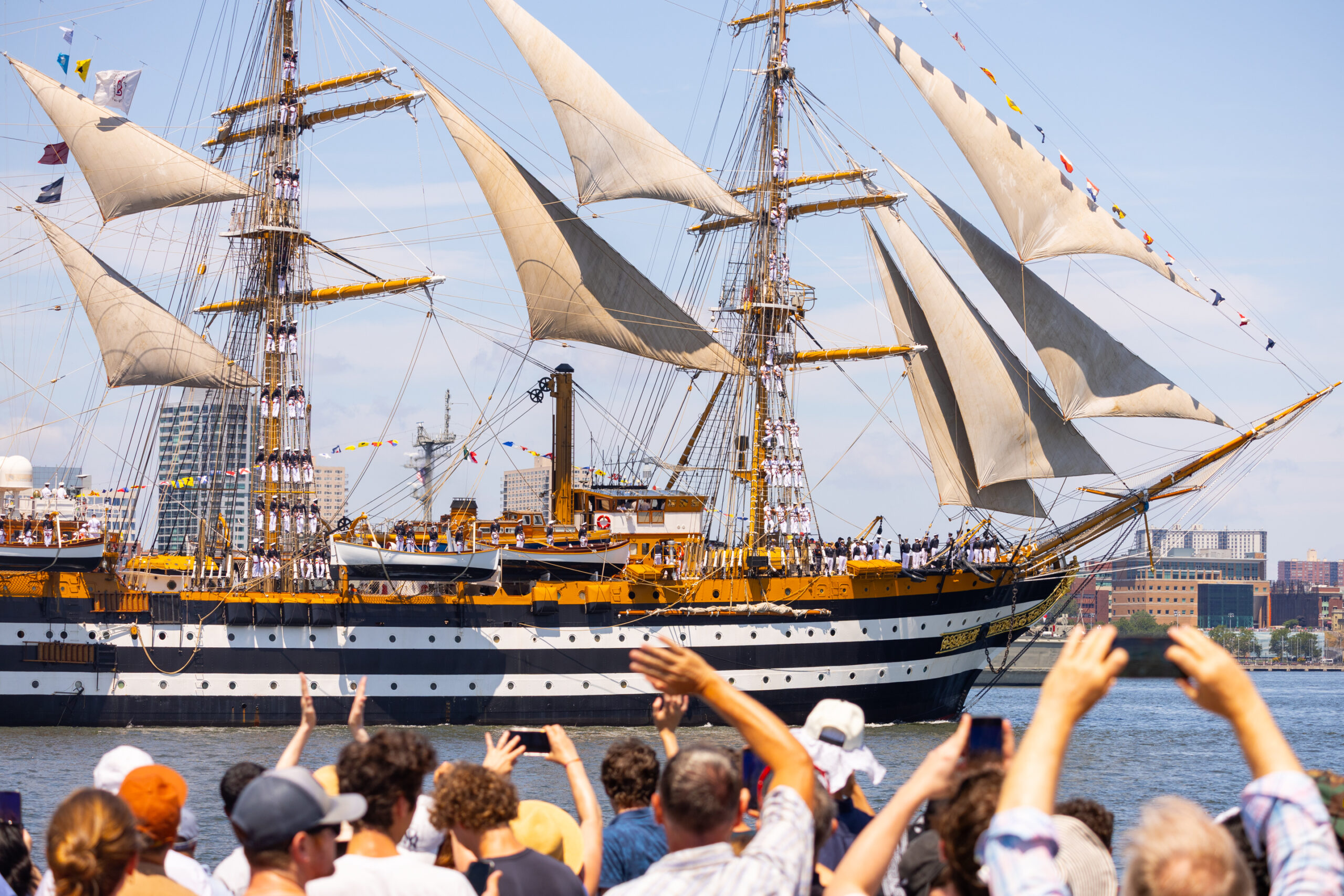 Crowds wave at tall ship sailing along Hudson River waterfront